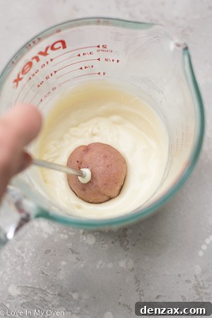 Strawberry cake pops being dipped in melted chocolate
