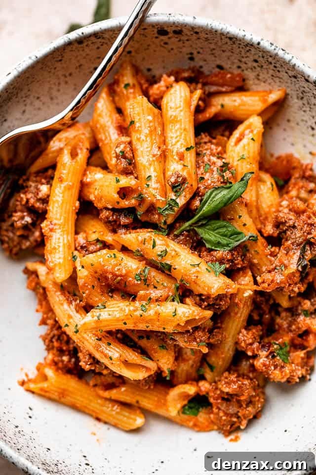 A close-up of a warm bowl of baked ziti, showing the melted cheese, rich red sauce, and textured pasta, ready to be enjoyed.