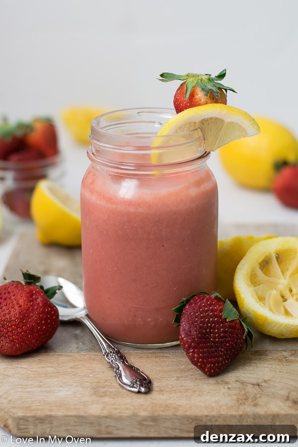 Close-up of freshly made strawberry lemon curd in a glass jar, showcasing its smooth, glossy texture and vibrant color.