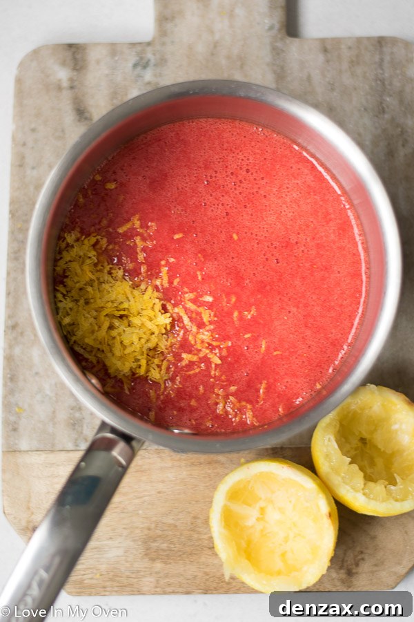 Strawberry lemon curd thickening in a saucepan on the stovetop, being continuously whisked by hand.