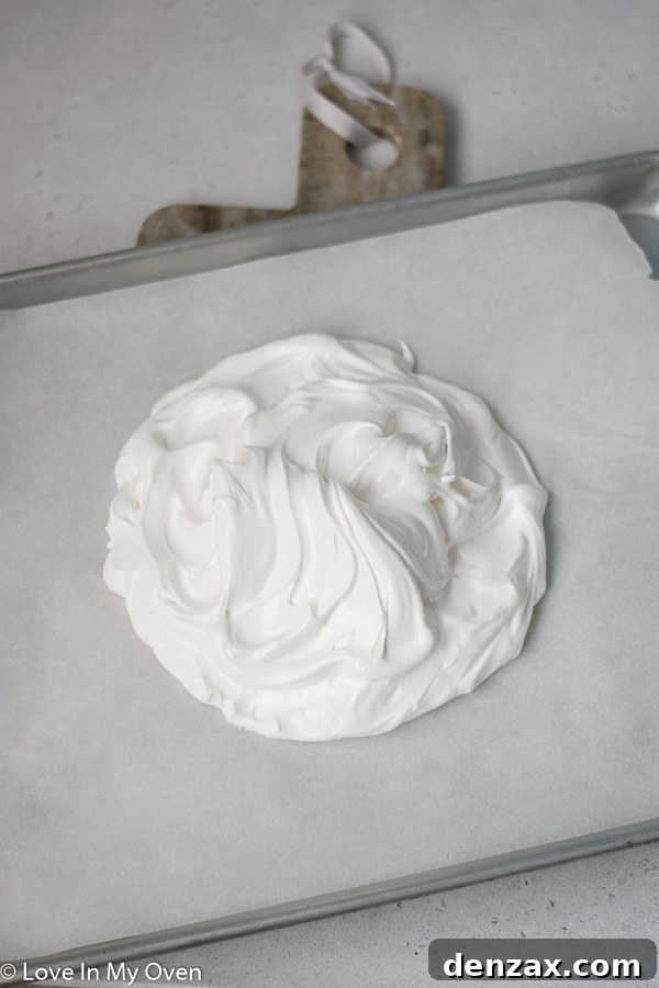 Meringue shaped into a round mound on parchment paper, ready for baking