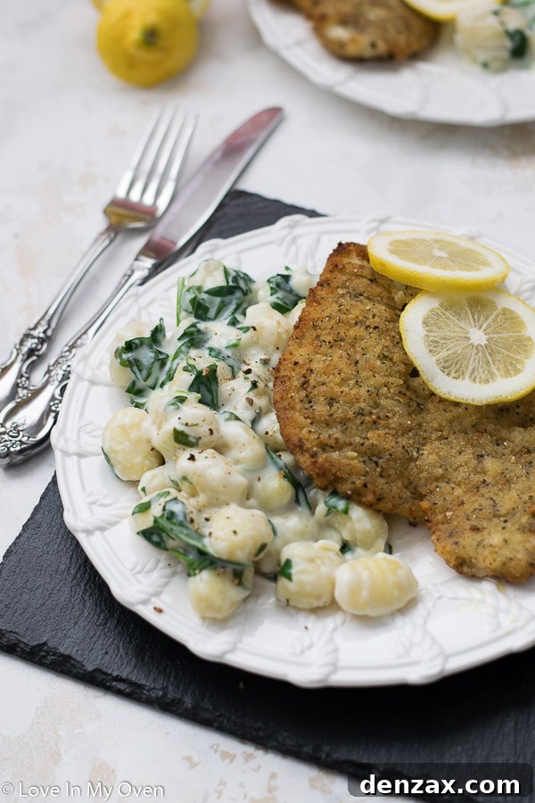 Two plates of creamy spinach gnocchi and lemon pepper sole, arranged for a romantic dinner.