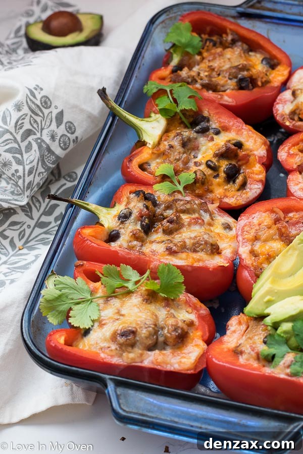 A serving of chorizo stuffed peppers with avocado and sour cream on a plate