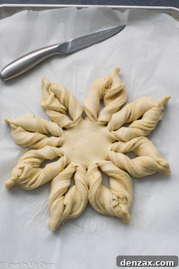 Pinching the ends of the twisted dough strips to seal them and complete the star shape.