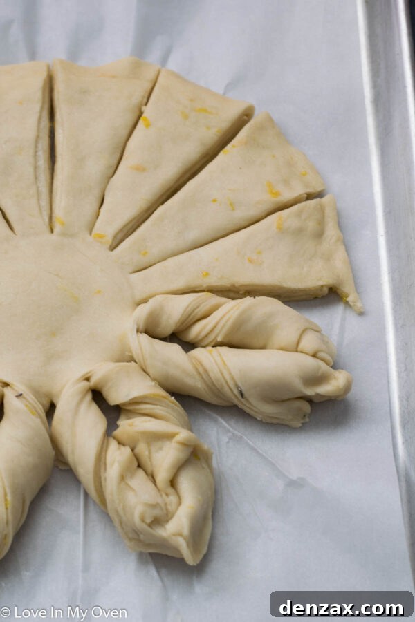 Twisting two adjacent dough strips to create the star bread's intricate design.