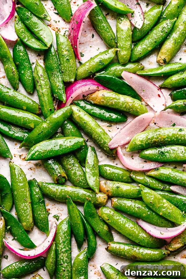 Top view of a serving bowl filled with beautifully roasted sugar snap peas and thinly sliced red onions, perfectly golden and tender-crisp.