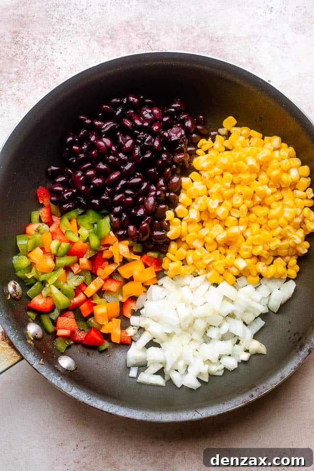 frying peppers, beans, corn, and onions in a frying pan