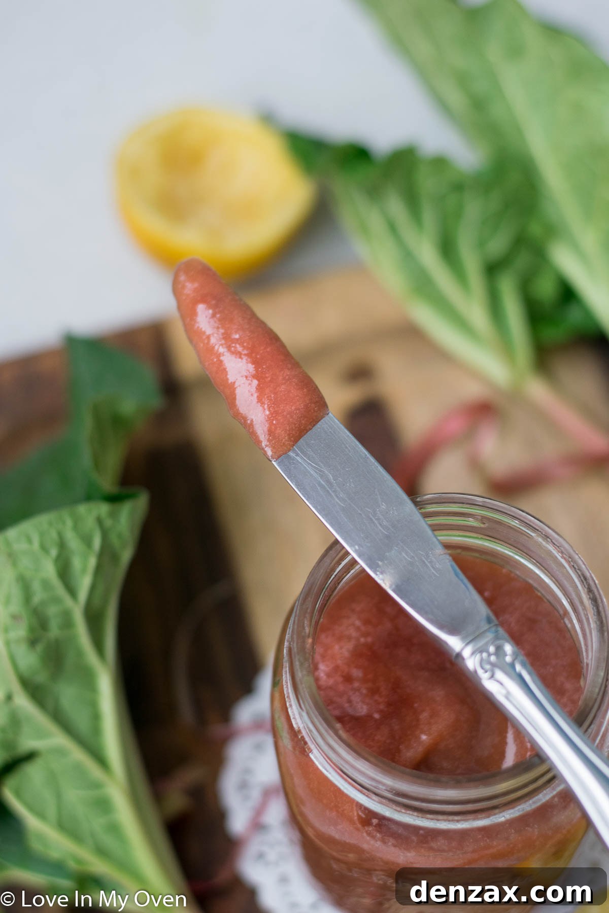 A jar of homemade rhubarb butter, garnished with a fresh rhubarb stalk.