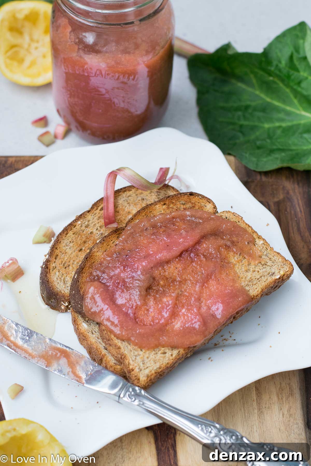 A spoonful of smooth rhubarb butter being scooped from a jar.