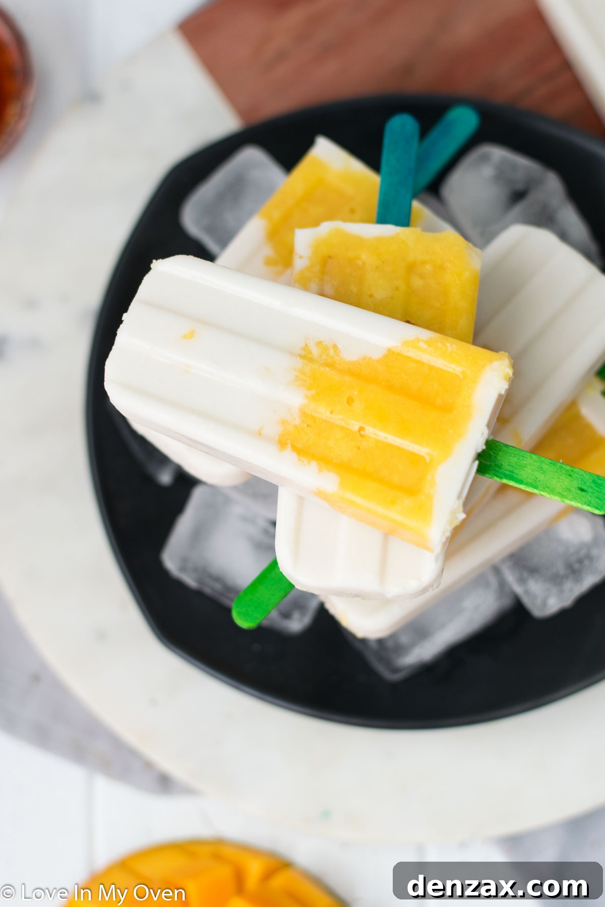 Layered mango coconut popsicles on a stick