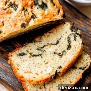 Top view of golden-brown spinach and feta no-yeast bread slices, showcasing herbs and cheese.