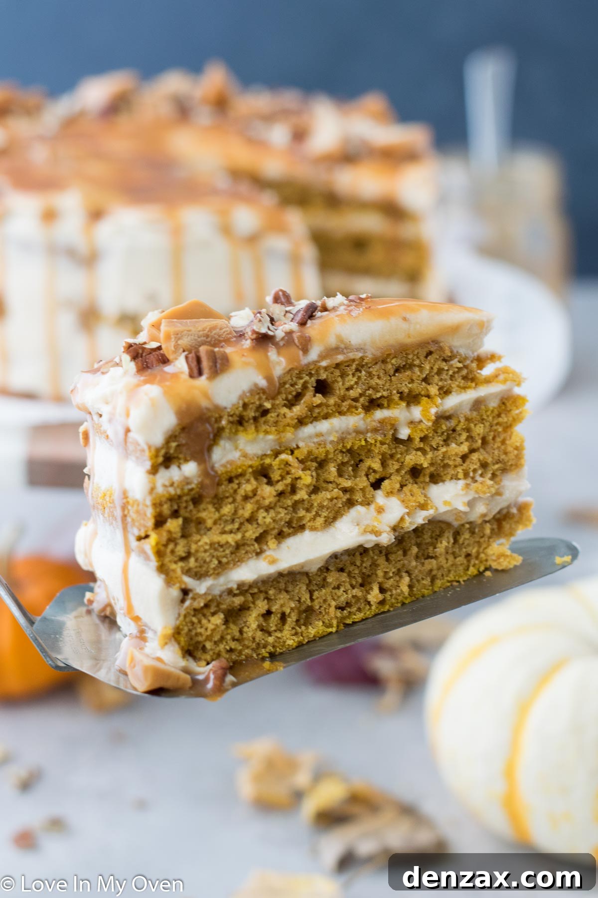 Close-up of a slice revealing the layers of pumpkin cake and caramel cream cheese frosting.