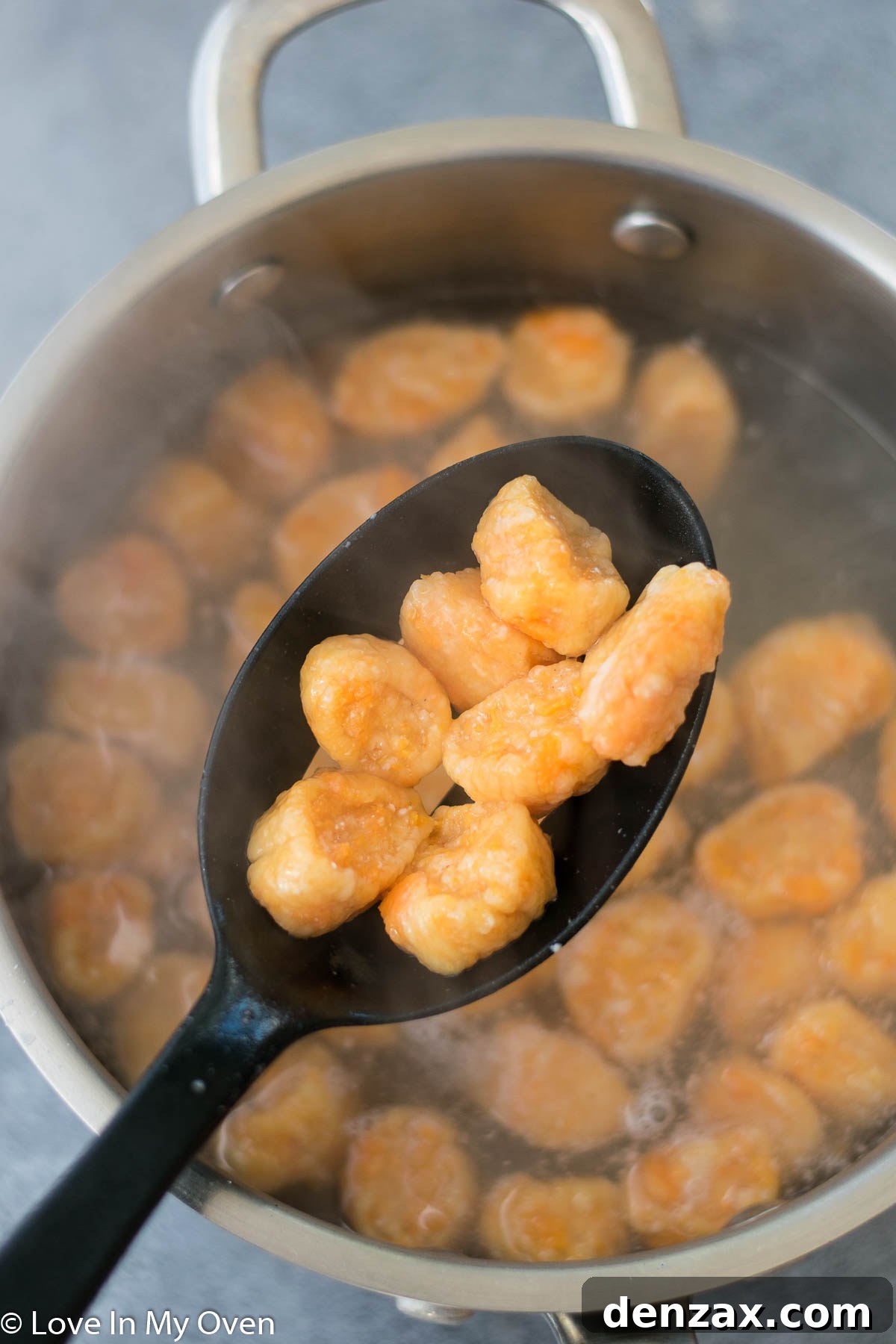 Cooked sweet potato gnocchi being transferred from boiling water to a skillet of sage butter