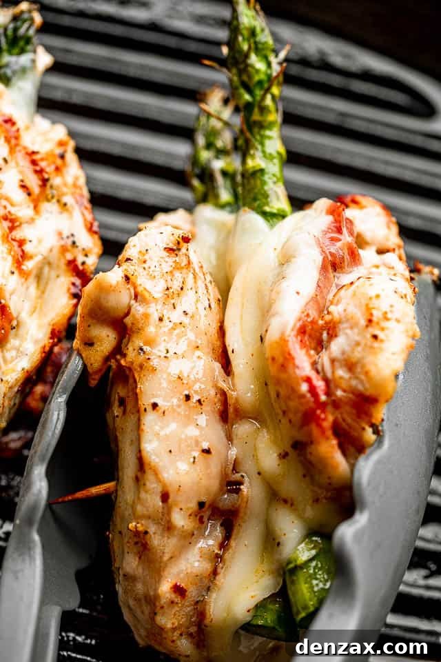 chicken breast stuffed with prosciutto, cheese, and asparagus held together with a pair of tongs