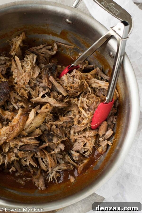 A serving of apple cider pulled pork with a side of coleslaw and a bun.