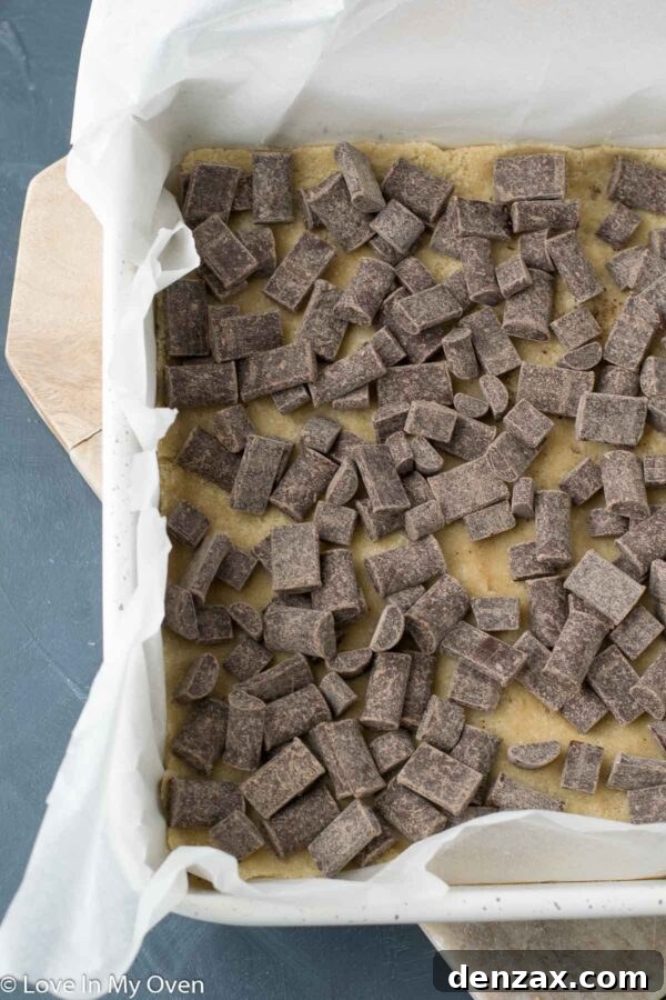 A close-up of the vegan chocolate layer topped with freshly chopped pecans, ready for the next step.