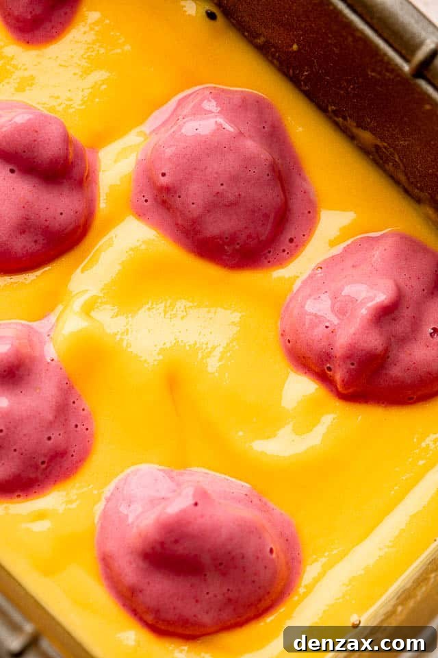 Close-up shot of a blended mango mixture topped with dollops of blended strawberry mixture, ready for swirling