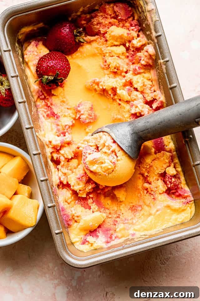 Top shot of mango strawberry frozen yogurt in a loaf pan with an ice cream scooper, showing the beautiful swirls