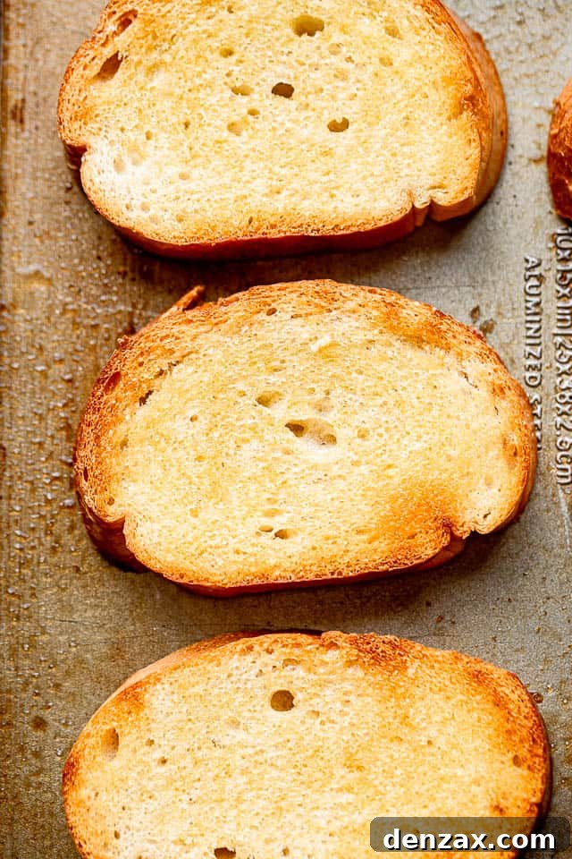A close-up view of perfectly toasted garlic bread slices, golden brown and ready for their fresh tomato topping, highlighting their irresistible texture.