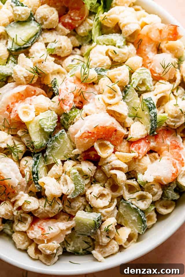 Close up shot of a vibrant Creamy Shrimp Pasta Salad brimming with plump shrimp, crisp cucumber slices, and small pasta, inviting to be eaten