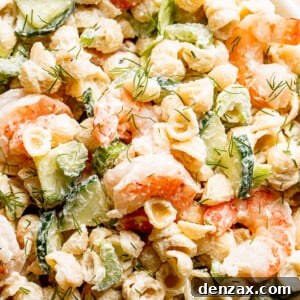 close up top shot of Creamy Shrimp Pasta Salad studded with sliced cucumbers and plump shrimp