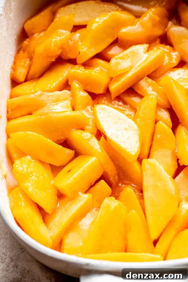 Fresh sliced peaches arranged beautifully in a glass baking dish, ready for the cake topping.