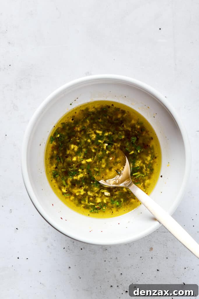 Mixing the vibrant lemon chicken marinade in a bowl, showing the blend of herbs, garlic, and liquids.