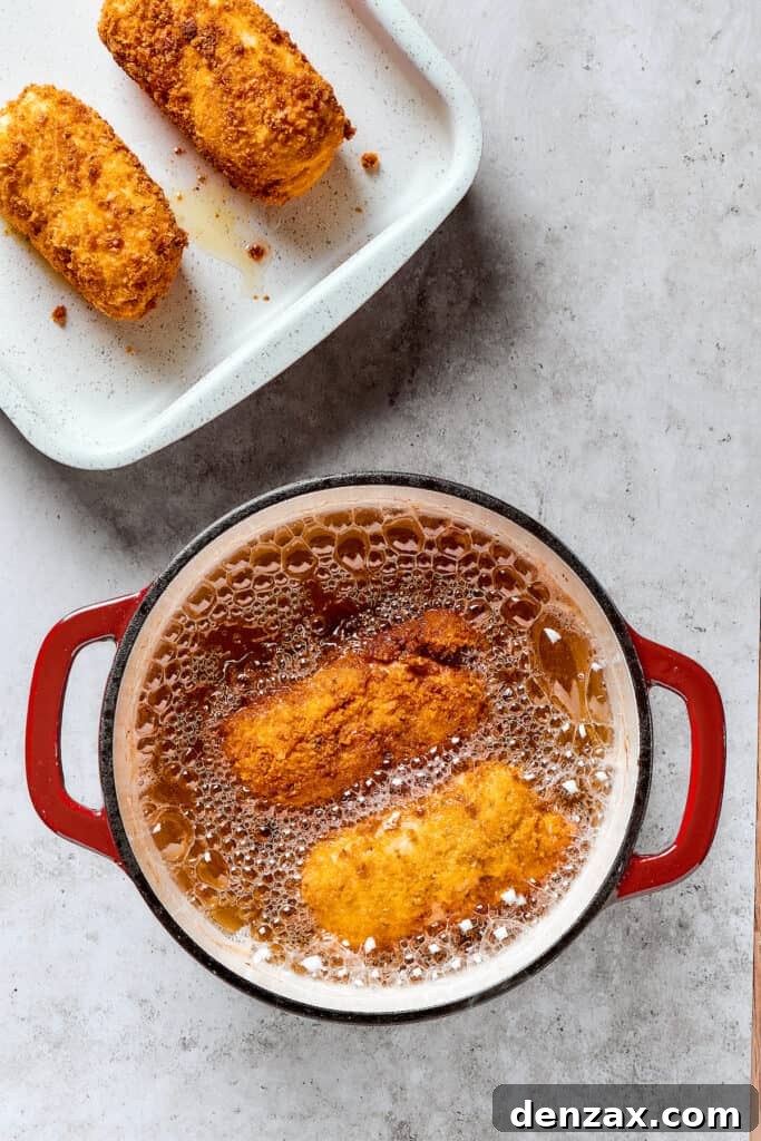 Deep-frying stuffed chicken breast in a Dutch oven until golden brown.