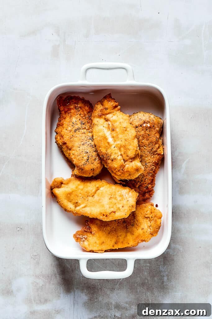 Breaded, browned chicken in a baking dish.
