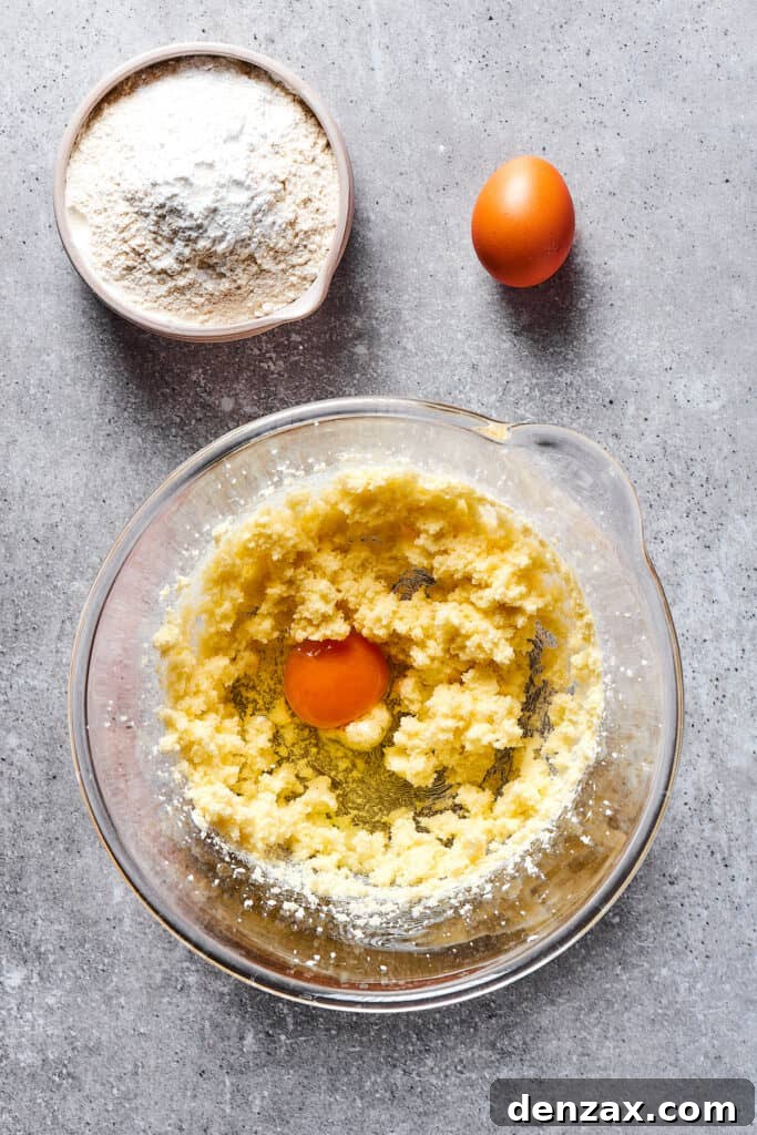 The process of beating eggs into creamed butter and sugar, showing the mixture becoming light and fluffy.