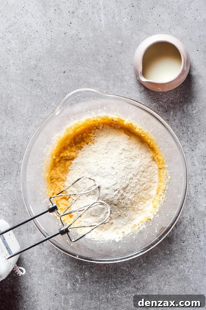 The process of mixing dry and wet ingredients in a large bowl, creating a smooth cupcake batter.