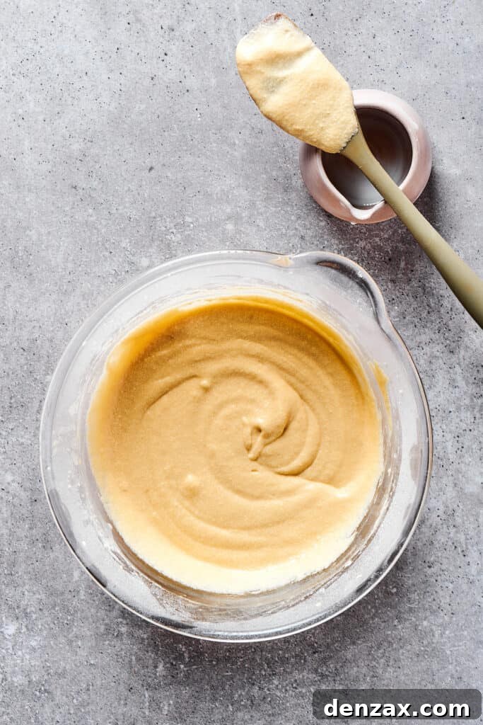 A large mixing bowl filled with smooth, pale yellow cupcake batter, ready for portioning.