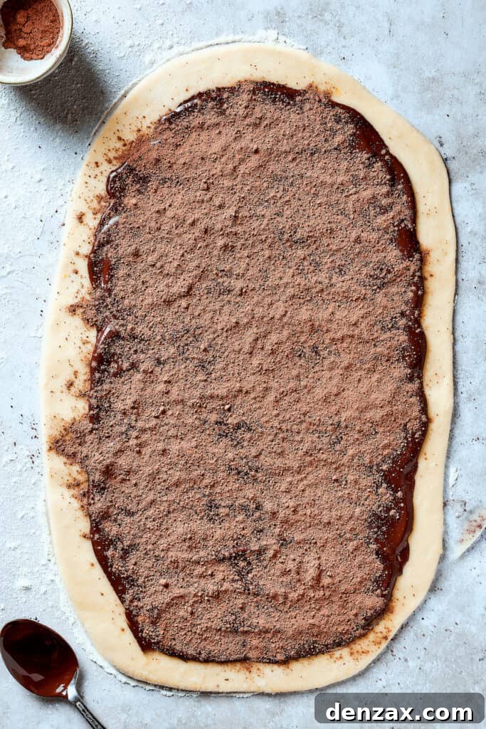Chocolate spread out over a rectangle of dough and sprinkled with cocoa powder.