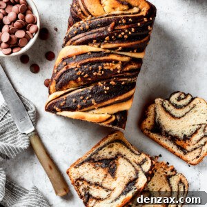A loaf of chocolate babka that has been partially sliced. The slices are laid out on the work surface along with a bread knife and a dish of chocolate chips.