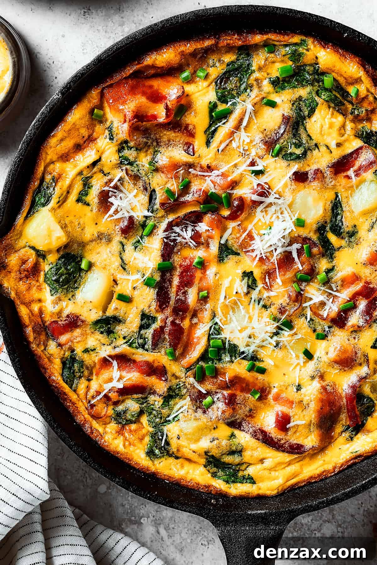 Close-up overhead view of a beautifully textured, fully-cooked frittata, showcasing its golden crust and visible ingredients, served directly in a cast-iron pan.