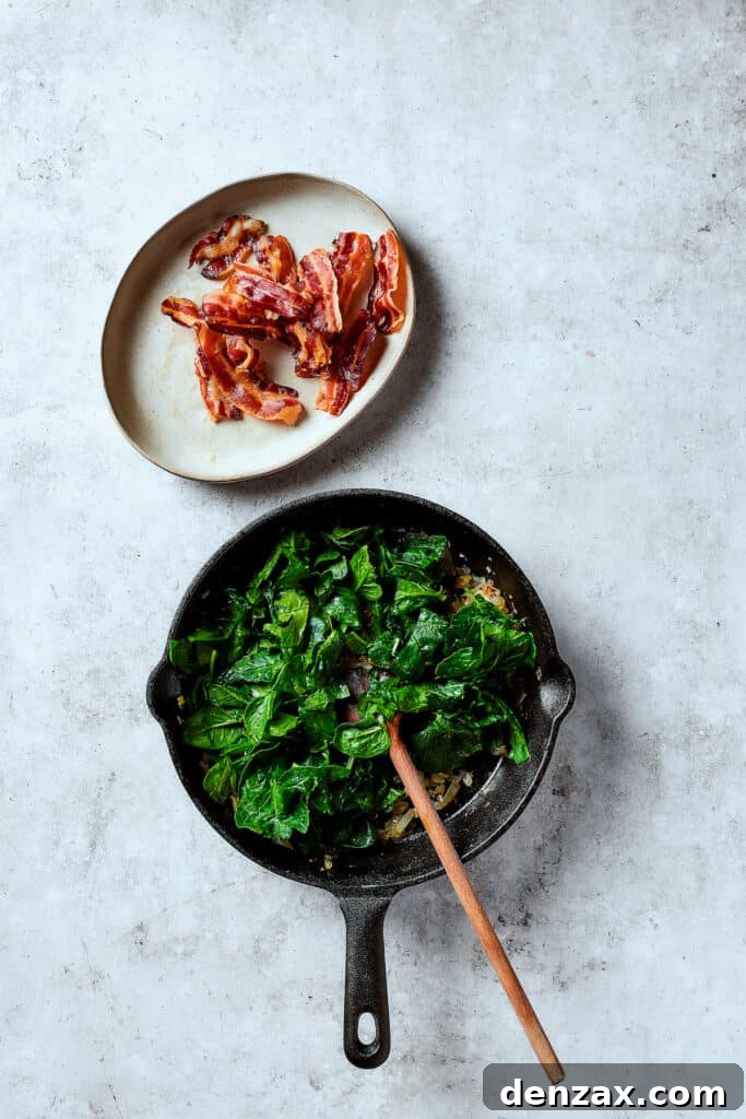 Fresh spinach wilting in a skillet with sautéed onions and garlic, creating a vibrant and savory base for the frittata.