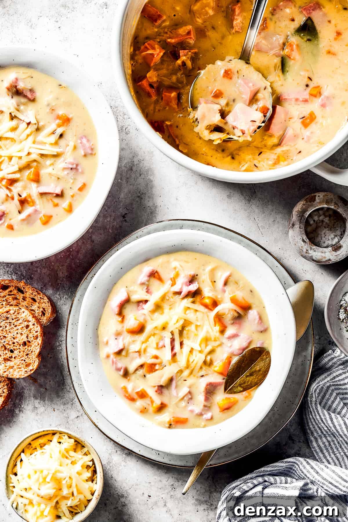 A pot of hearty Reuben soup next to two steaming bowls, topped with melted cheese and croutons.