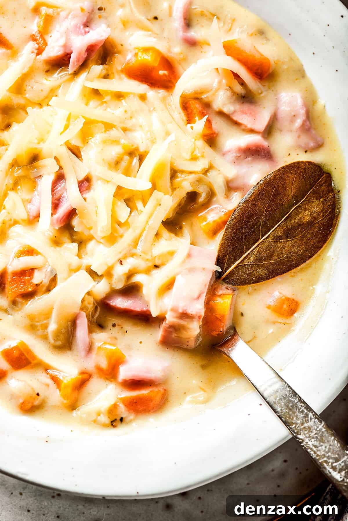 Close-up of a bowl of creamy Reuben soup, richly garnished with shredded Swiss cheese, showcasing the blend of corned beef and sauerkraut.