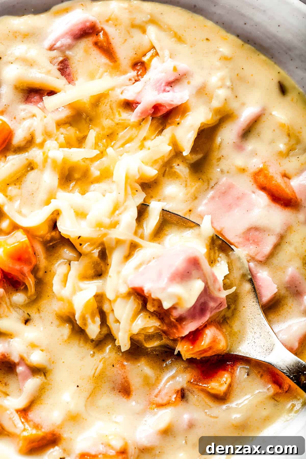 Close-up shot of creamy Reuben soup with melted Swiss cheese and a spoon, highlighting its inviting texture.