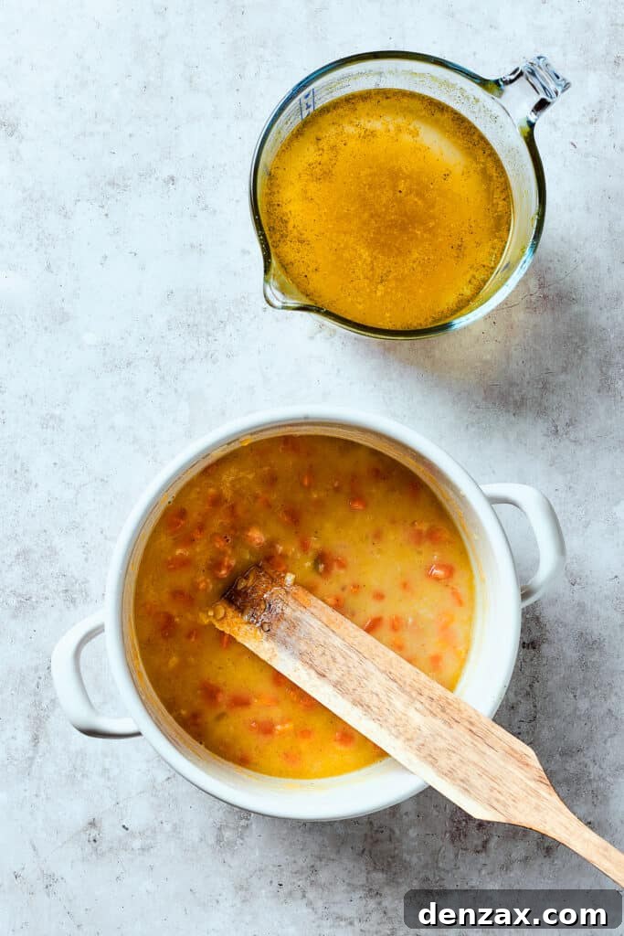 Slowly pouring broth into the soup pot, stirring to combine smoothly.