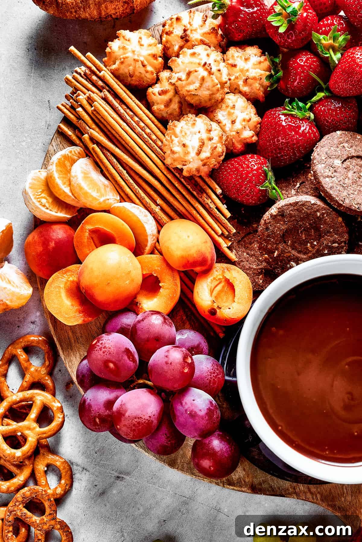 A wooden charcuterie board with sweet and savory dippers and chocolate sauce.