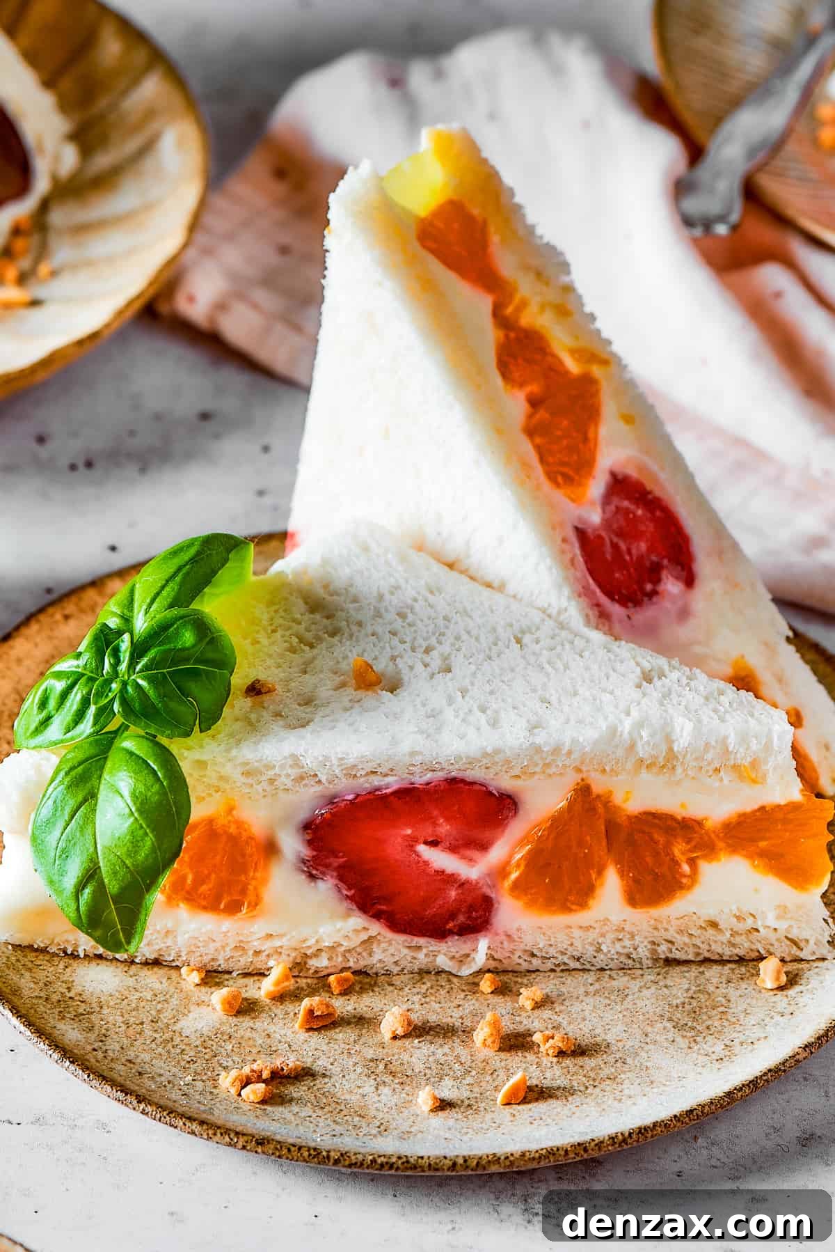 A perfectly cut fruit sando featuring vibrant mandarin oranges and strawberries, on a white plate.