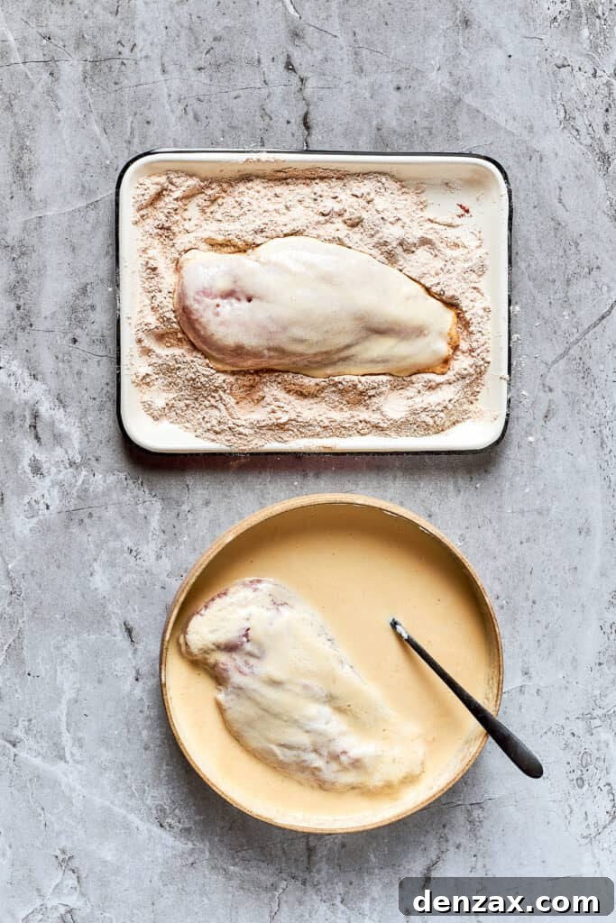 Dredging chicken in a bowl of seasoned flour, ensuring a thick coating.