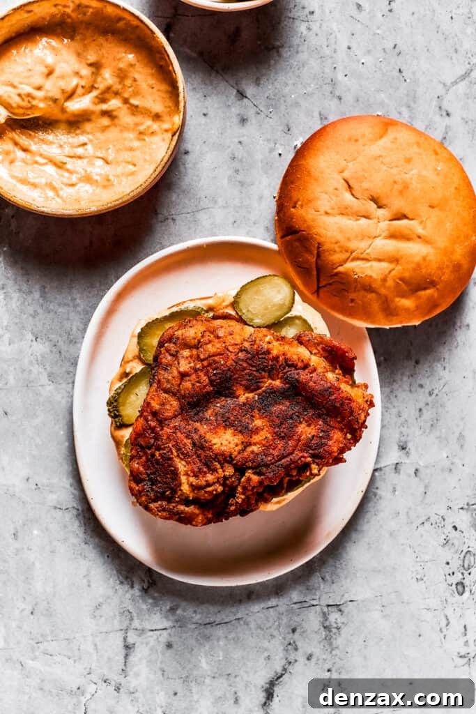 Assembling a copycat KFC chicken sandwich by layering ingredients on a bun.