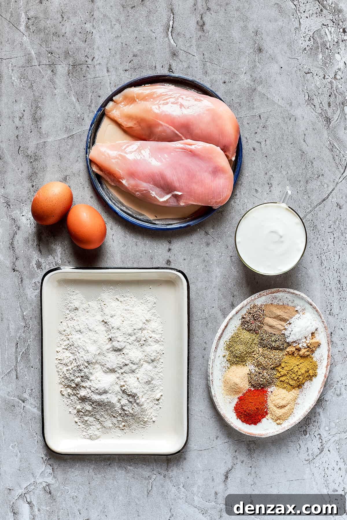Individual ingredients for the Copycat KFC Chicken Sandwich: chicken breast, buttermilk, eggs, flour, and a selection of spices.