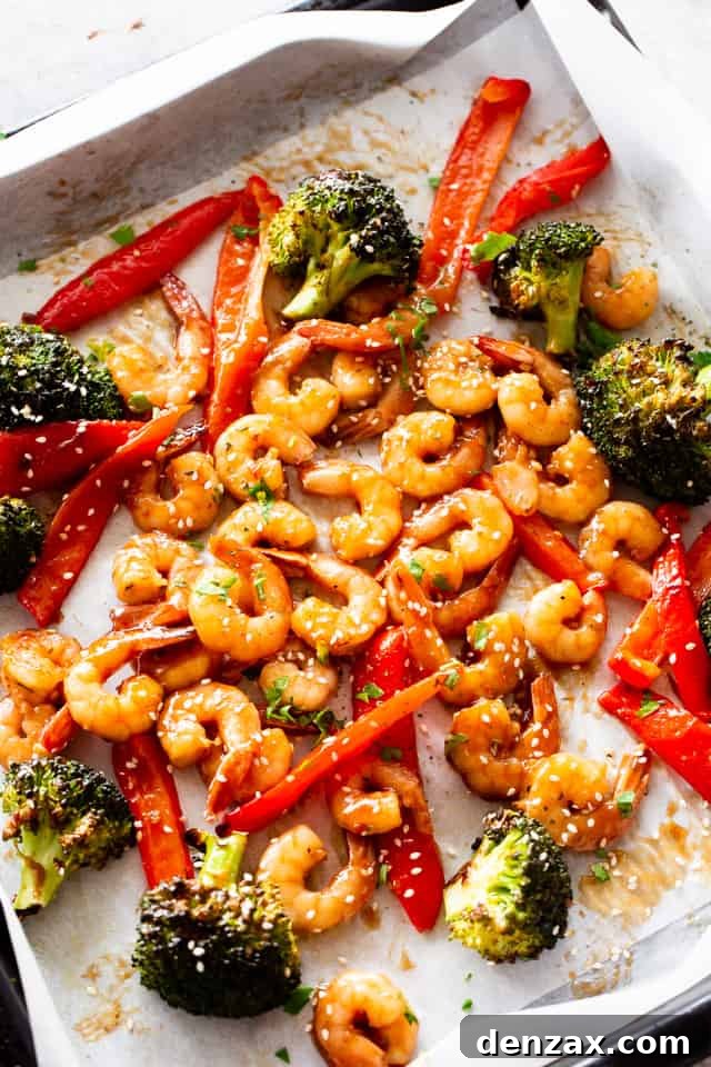 Overhead shot of Sheet Pan Teriyaki Shrimp Stir Fry with rice and garnishes, glistening with sauce.