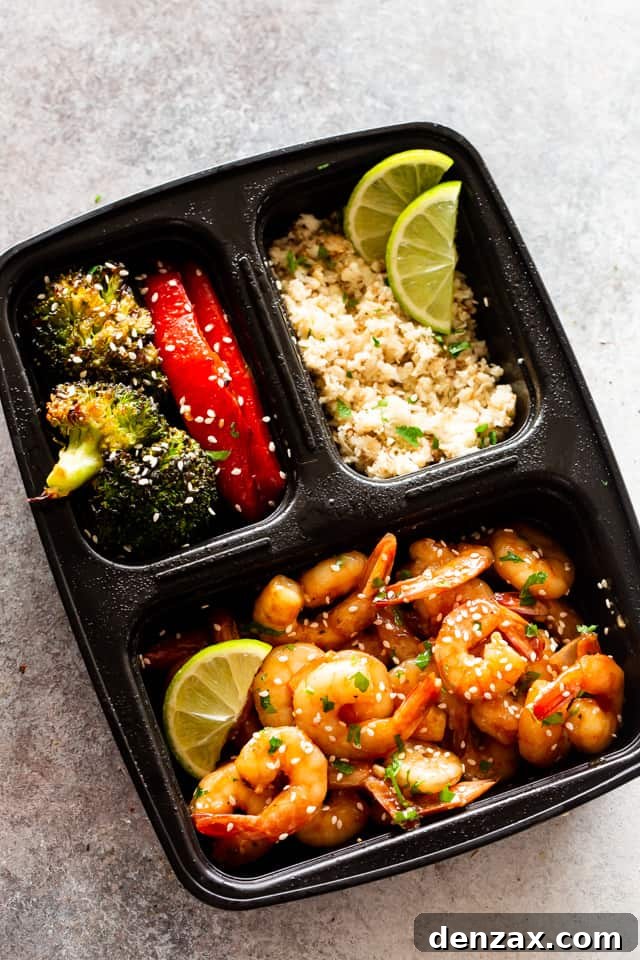Photo of cooked shrimp, stir-fried veggies, and rice in a black container, neatly portioned for meal prep.