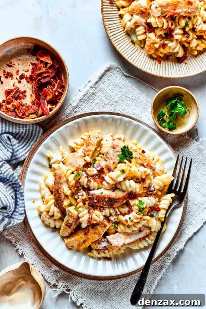 An overhead shot of chicken bacon ranch pasta served on dinner plates, garnished with fresh herbs.