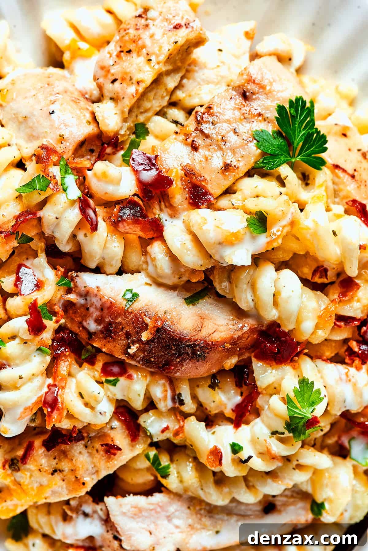 Close-up shot of creamy chicken bacon ranch pasta garnished with fresh parsley, highlighting its rich texture.