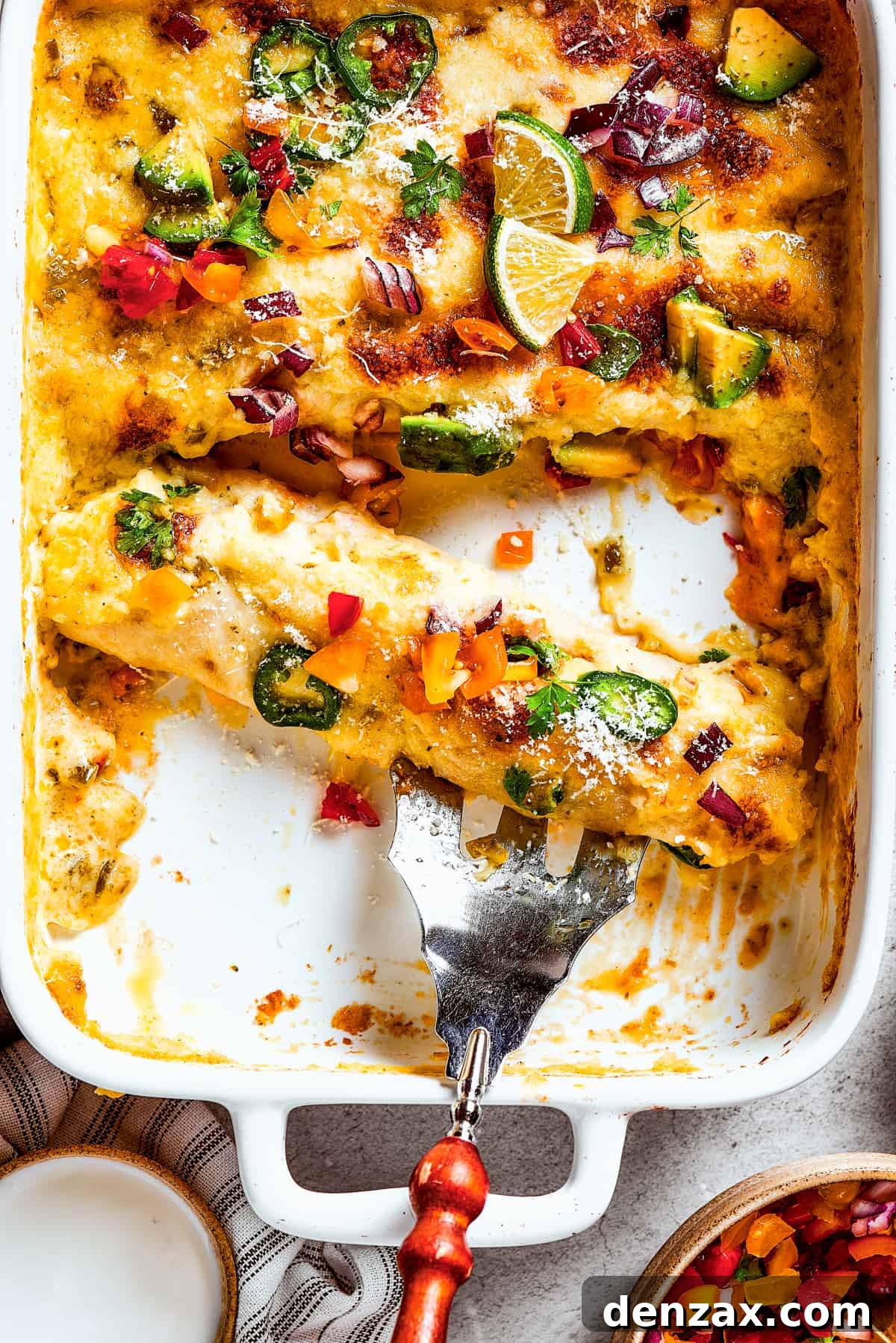 A serving fork resting in a dish of homemade shrimp enchiladas, showcasing melted cheese and a vibrant green sauce.